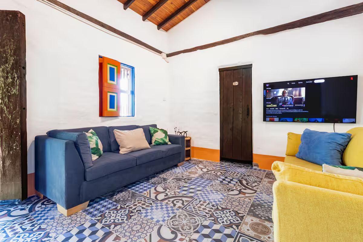La sala — baldosa de patchwork, sofá azul, silla amarilla